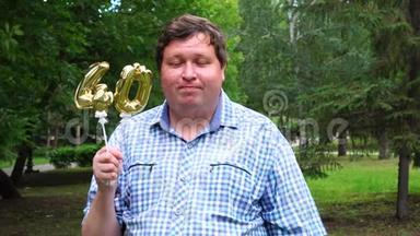 大个子拿着金色气球，把40号放在户外。 40周年庆祝晚会